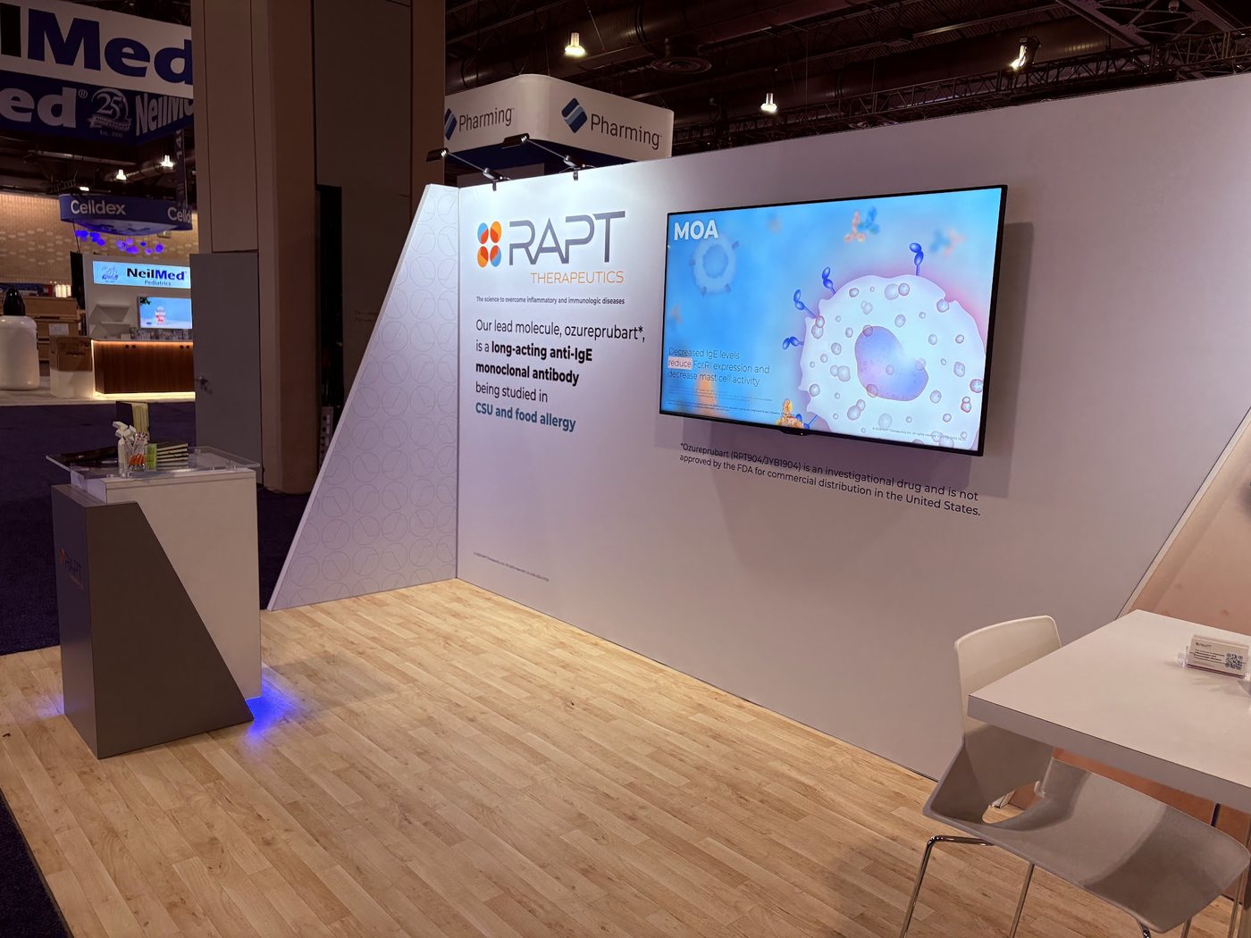RAPT Therapeutics booth with a wall-mounted display playing a mechanism of action animation